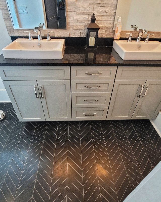 Remodeled Asbury Park, NJ bathroom dual vanity with a black herringbone pattern tile floor.