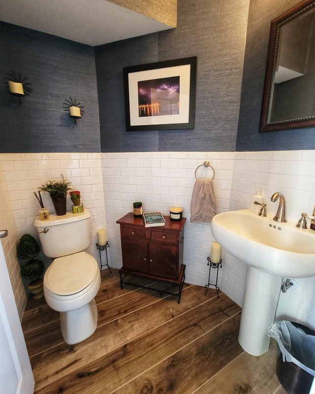 Small bathroom renovation in Asbury Park, NJ. The upper half of the wall is a textured blue wallpaper while the bottom half is a white subway pattern tile. The floor is wood LVP.