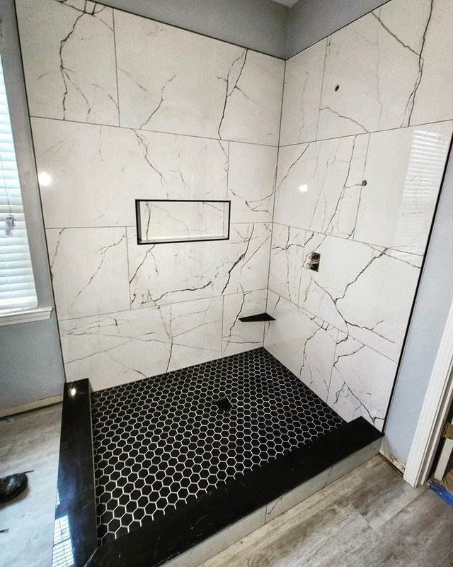 Picture of a newly remodeled shower in Asbury Park, NJ. The floor is a black beehive pattern. The walls are a beautiful white marble.