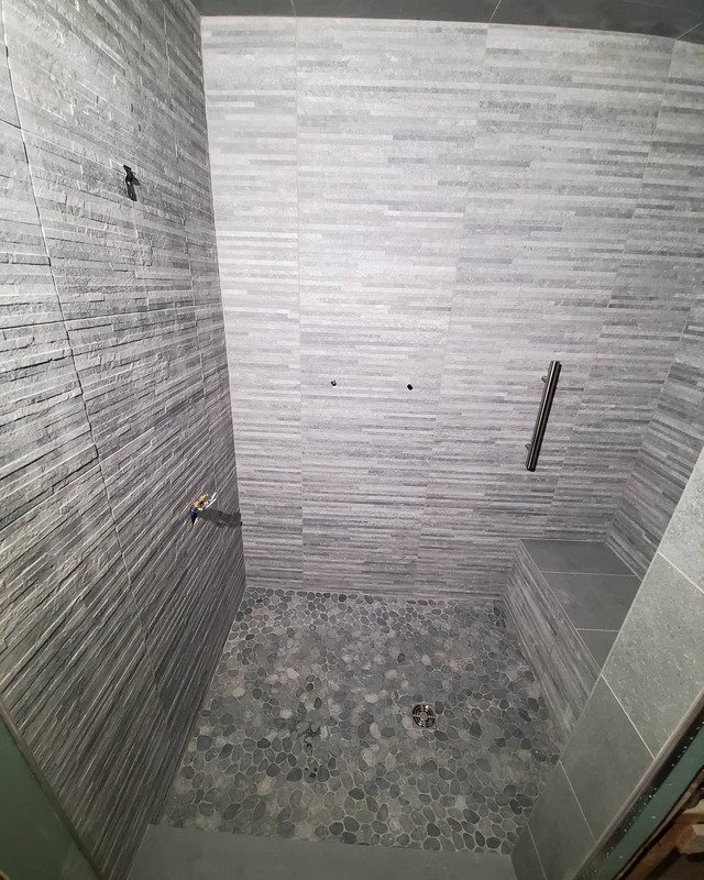 Newly renovated Asbury Park, NJ shower with white and gray stone tiles.